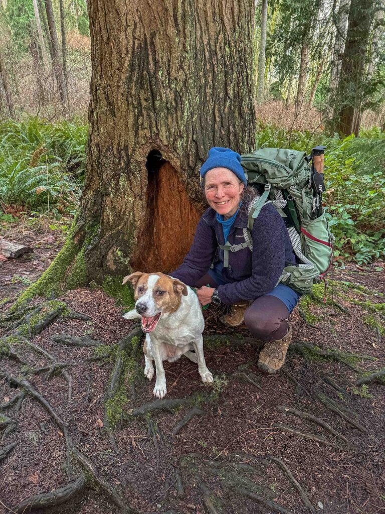 Ajax and I pause for a photo in front of a partly hollowed-out tree. I trust what the trail teaches: slow down, listen, appreciate.