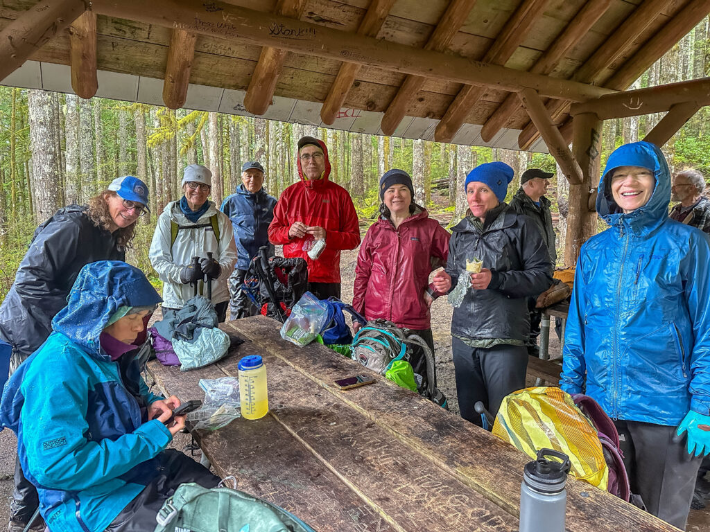 Wet but happy, hungry hikers hurriedly huddle for a bite at Wallace Lake/Falls before the last push to the cars. Intentions? Fun!